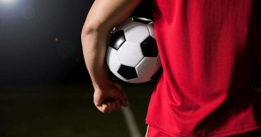 A person in a red shirt holds a football under their arm. The text reads, Leiper Gupta Family Lawyers (LGFL) The Link: Domestic Abuse & Football, over a gradient maroon background.